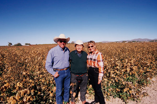 在美国新墨西哥州栽培优质有机棉的阿尔瓦雷斯夫妇与大正纺织株式会社的近藤健一的合影。该公司纺纱用的棉花来自夫妇俩栽培的有机棉。